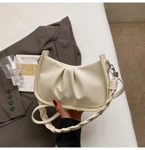 Detail of off-white cloud bag with lychee texture and braided handle in lifestyle setting