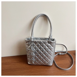 Détail d'un sac seau matelassé argenté orné de breloques étoiles métalliques
