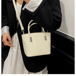 Model wearing a creamy white bucket bag with pebble leather texture and silver beads