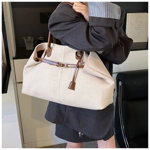 Detail of canvas tote bag with brown leather handles and gold metal buckle accents