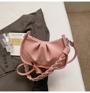 Detail view of the pink pleated cloud bag with a chunky woven handle and crossbody strap