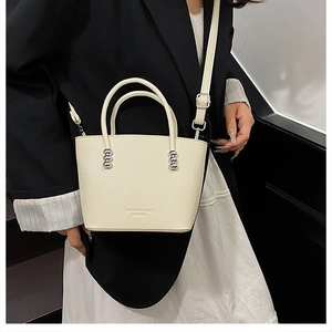 Detail view of cream bucket bag with lychee grain leather and silver metal studs