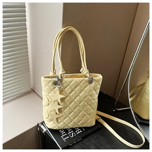 Détail d'un sac seau matelassé jaune clair avec breloques étoiles et bandoulière réglable