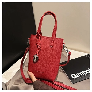 Détail du sac rouge en similicuir grainé avec breloque en forme de cœur et nœud élégant