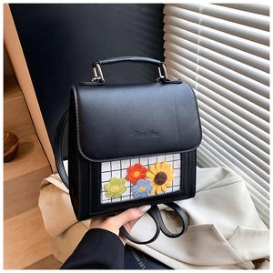 Dettaglio dello zaino in PU nero con ricamo a girasole e design a patta