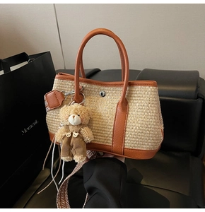 Gros plan d'un sac seau tressé beige avec anses en cuir marron et breloque ourson