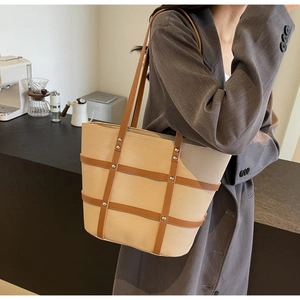 Canvas tote bag with brown leather straps shown on shoulder for a stylish casual look