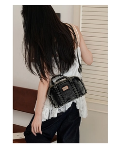 Sac Boston en denim noir délavé avec étiquette orange porté en bandoulière décontractée
