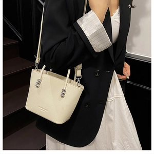 Detail of off-white bucket bag featuring lychee grain texture and silver bead accents