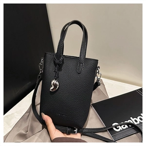 Détail du mini sac noir en cuir grainé avec breloque cœur argentée et fine bandoulière