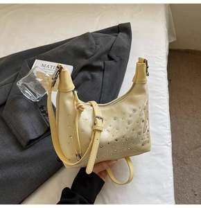 Detail of buttery yellow hobo bag with rhinestone studs and knotted strap adjustment buckle