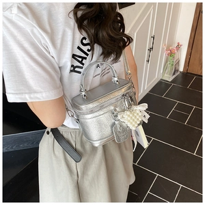 Detail of silver metallic pleated bucket bag with pearl heart and lace ribbon accents