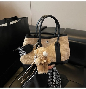 Détail du cabas en paille avec bordures en cuir noir et breloque ours en peluche