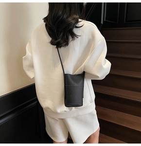 Detailed back view of a black pebble leather mini crossbody bucket bag on a model