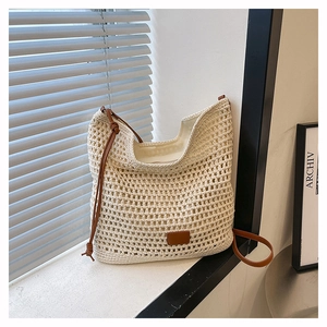 Detail of beige crochet woven tote with brown leather strap and intricate mesh texture