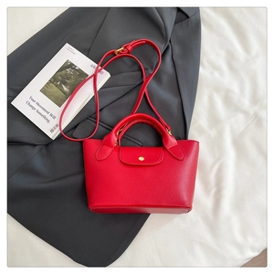 Detailed view of red lychee pattern tote bag on a blazer with gold hardware accents