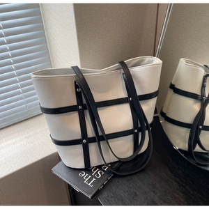 Detailed shot of black and white canvas tote bag with leather straps and silver metal rivets
