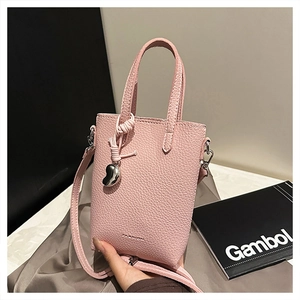 Détail du petit sac rose en cuir grainé avec un pendentif en forme de cœur argenté