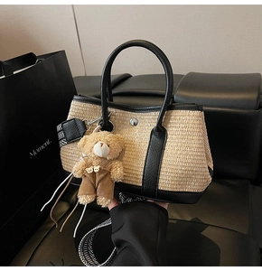 Détail du sac seau en paille avec bordure cuir noir, charm ours et bandoulière