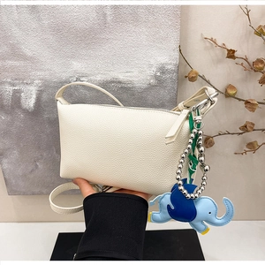 Dettaglio della borsa a cuscino in pelle martellata bianco crema con charm elefante blu
