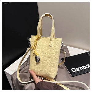 Détail d'un sac en cuir jaune clair avec motif litchi et pendentif coeur argenté