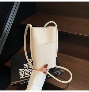 Detail of white litchi pattern leather crossbody phone bag on wooden steps