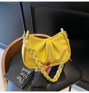 Detail of yellow pleated crescent bag featuring lychee texture leather and woven handle