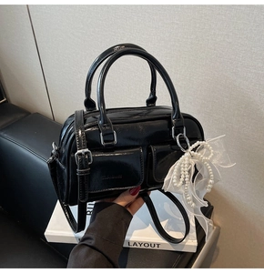Detail of black patent leather Boston bag with silver hardware and pearl bow charm