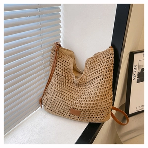 Detail of woven straw tote bag featuring brown leather straps and interior lining