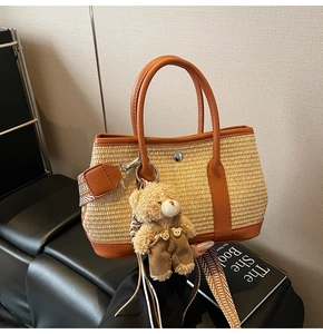 Vue détaillée du sac cabas en paille tressée avec garniture en cuir brun et ours en peluche