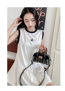 Sac polochon en denim porté avec une robe blanche montrant les options de porté main et bandoulière