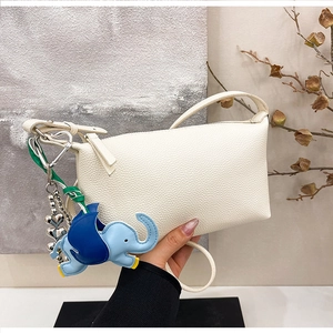 Dettaglio della borsa in pelle bianca con ciondolo a forma di elefante blu e catena con cuore