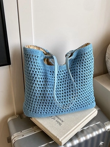 Light blue woven beach tote bag with leather straps and beige inner lining on a suitcase