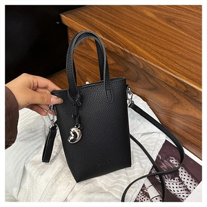 Détail du sac de téléphone en cuir noir avec breloque cœur et poignée supérieure