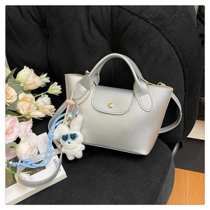Close-up of silver pebble grain tote bag with cute plush bunny charm on black background