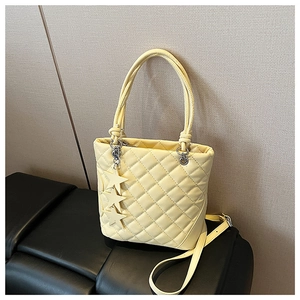 Détail du sac seau matelassé jaune clair avec breloques étoiles et bandoulière