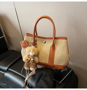 Détail du sac seau en paille tissée avec garniture en cuir brun et pendentif ours