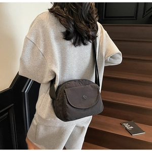 Nahaufnahme der anthrazitgrauen Nylon-Umhängetasche mit Metall-Logo und Schultergurt