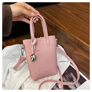 Détails d'un mini sac en cuir rose à grain litchi avec pendentif cœur et bandoulière