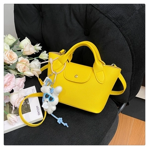 Close-up of a mini yellow tote bag with lychee texture and a cute rabbit pendant