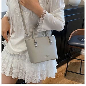 Close-up of light gray bucket bag with lychee texture and silver hardware details