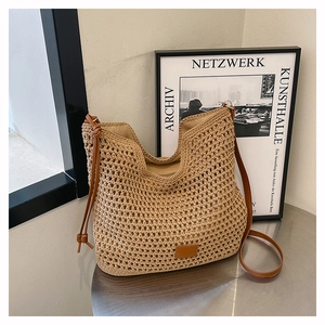 Detail of hand-woven hobo bag with brown leather drawstring and strap on metal table
