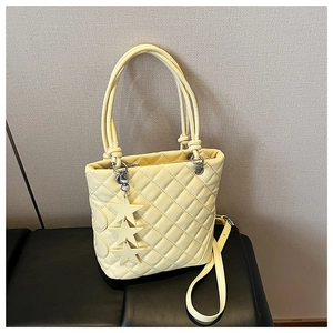 Détail d'un sac seau jaune pâle avec motif matelassé en losange et pendentifs étoiles