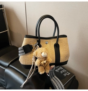Détail du sac seau en paille tissée avec bordure en cuir noir et pendentif ours en peluche