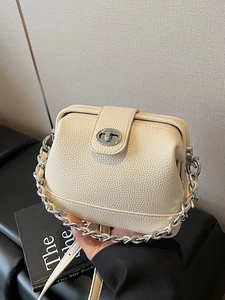 Chic cream leather bucket bag with silver chain handle and adjustable crossbody strap