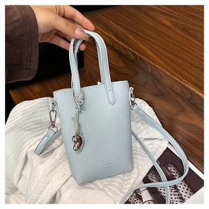 Détail d'un mini sac de téléphone en cuir bleu clair avec breloque coeur argentée
