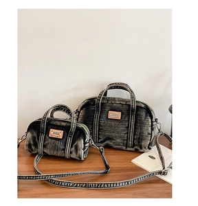 Détail de deux sacs bowling en denim délavé de tailles différentes sur bois