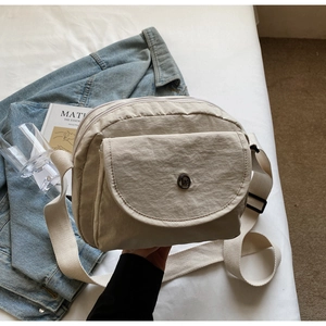 Detailansicht der beigen Nylon-Umhängetasche mit Klapptasche auf ästhetischem Hintergrund