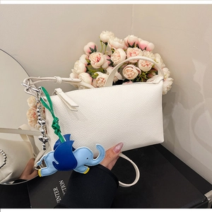 Dettaglio della pelle bianca a grana litchi e del ciondolo a forma di elefante blu