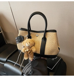 Détail du sac seau en paille beige avec finitions en cuir noir, ours en peluche et bandoulière